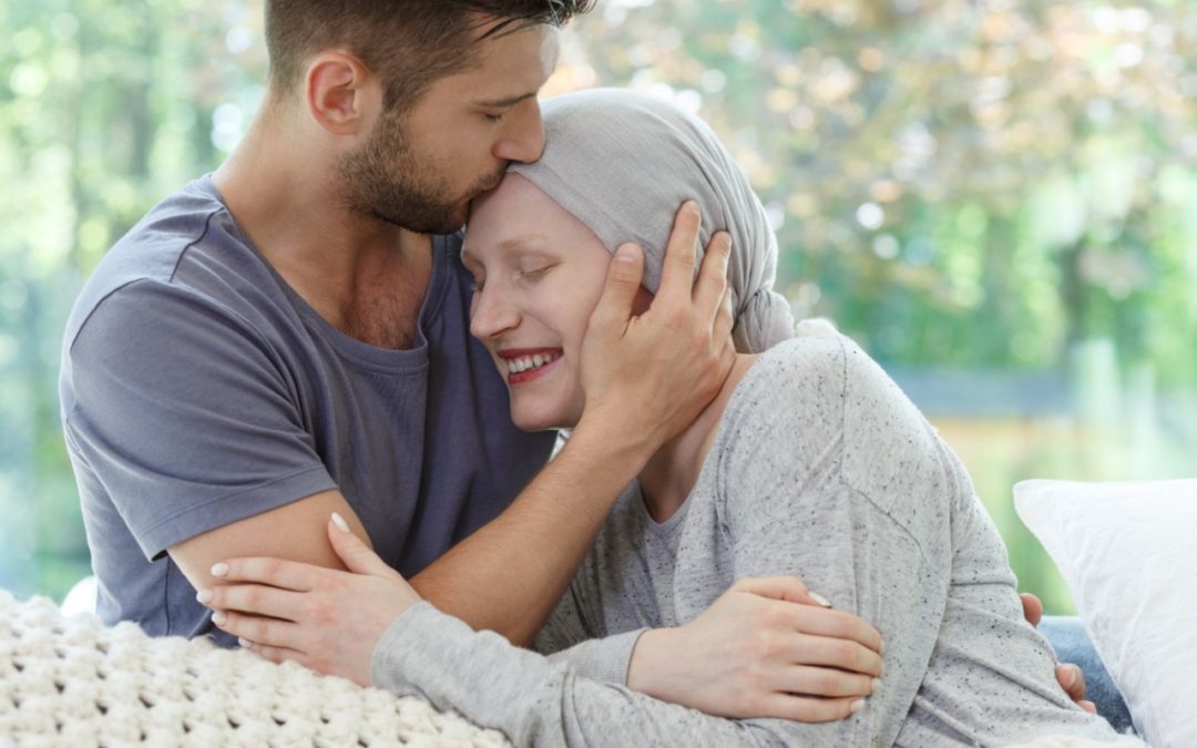 Hombre besa en la frente a su pareja enferma de cáncer